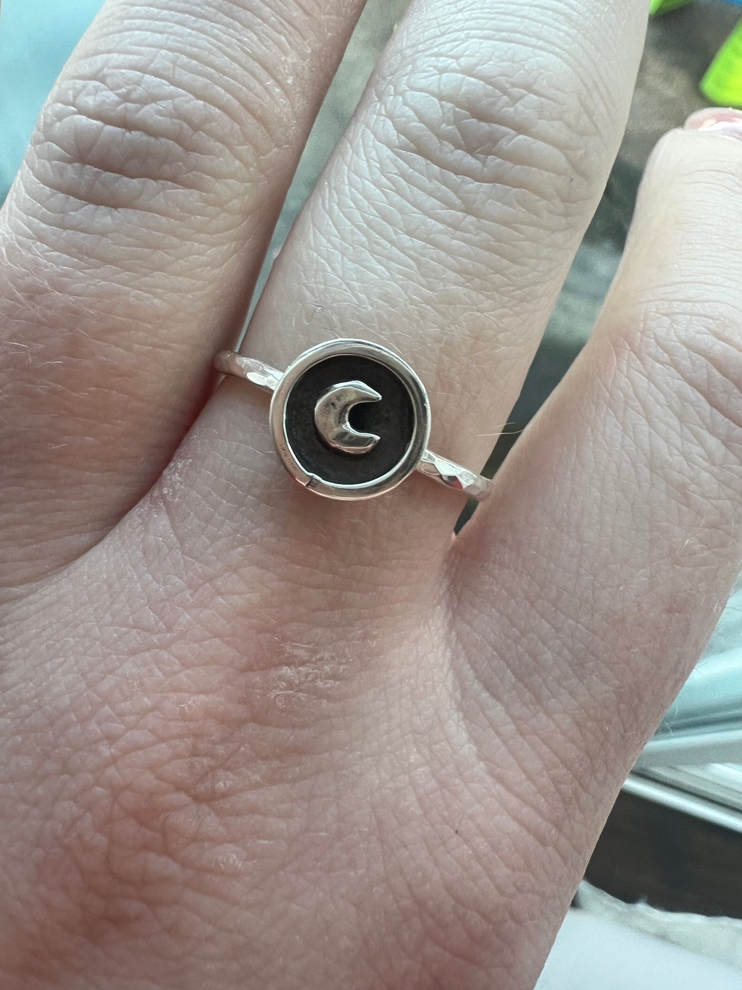 Silver ring with a moon design on a person's finger